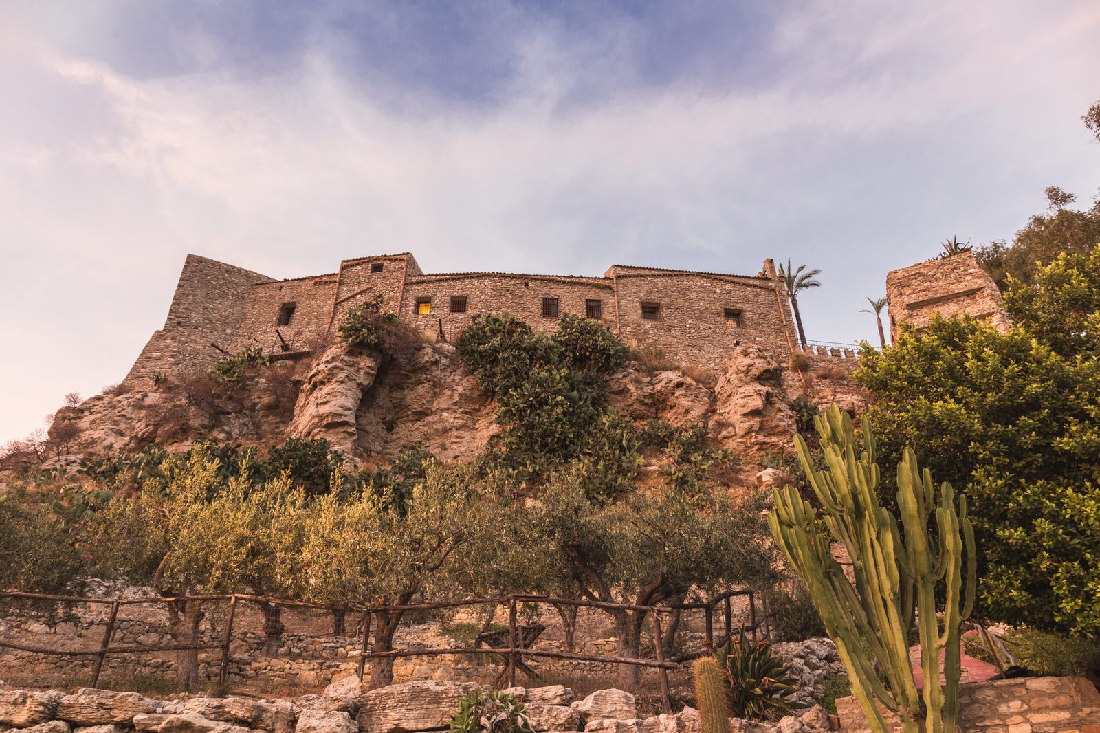 Le mura del Castello Chiaramonte che si ergono sulla rocca tra la macchia mediterranea